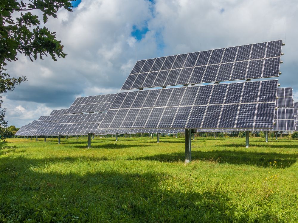 Placas solares em campo aberto conectadas a um conversor de energia solar para transformar corrente contínua em alternada na rede elétrica.