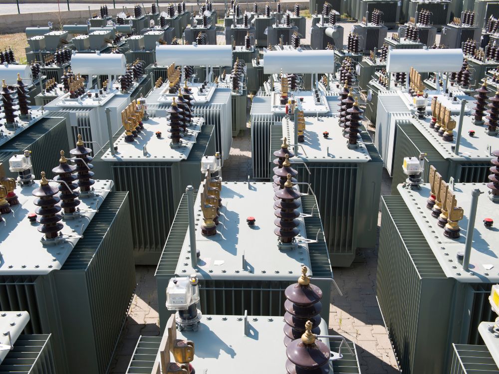 Transformadores de potência organizados em pátio industrial, ilustrando o contexto de aplicação da diferença entre TP e TC em sistemas elétricos.