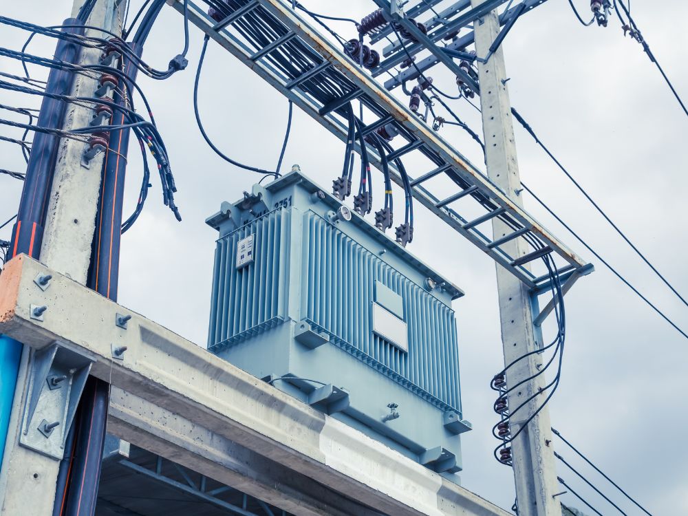 Transformador instalado em uma linha de distribuição elétrica, representando a infraestrutura necessária para fornecer energia estável, ponderando entre transformador ou autotransformador.