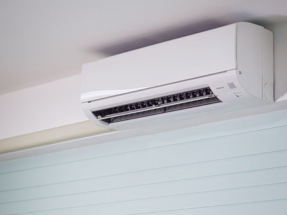 Aparelho de ar-condicionado split branco instalado próximo ao teto, com a saída de ar aberta em um ambiente interno.